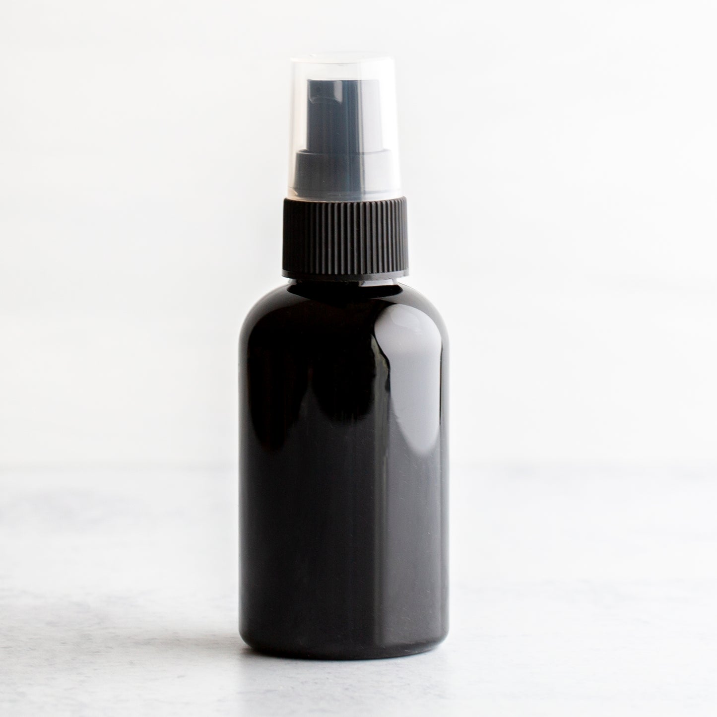 2 oz Black PET Boston Round Bottle with 20-410 Black Treatment Pump