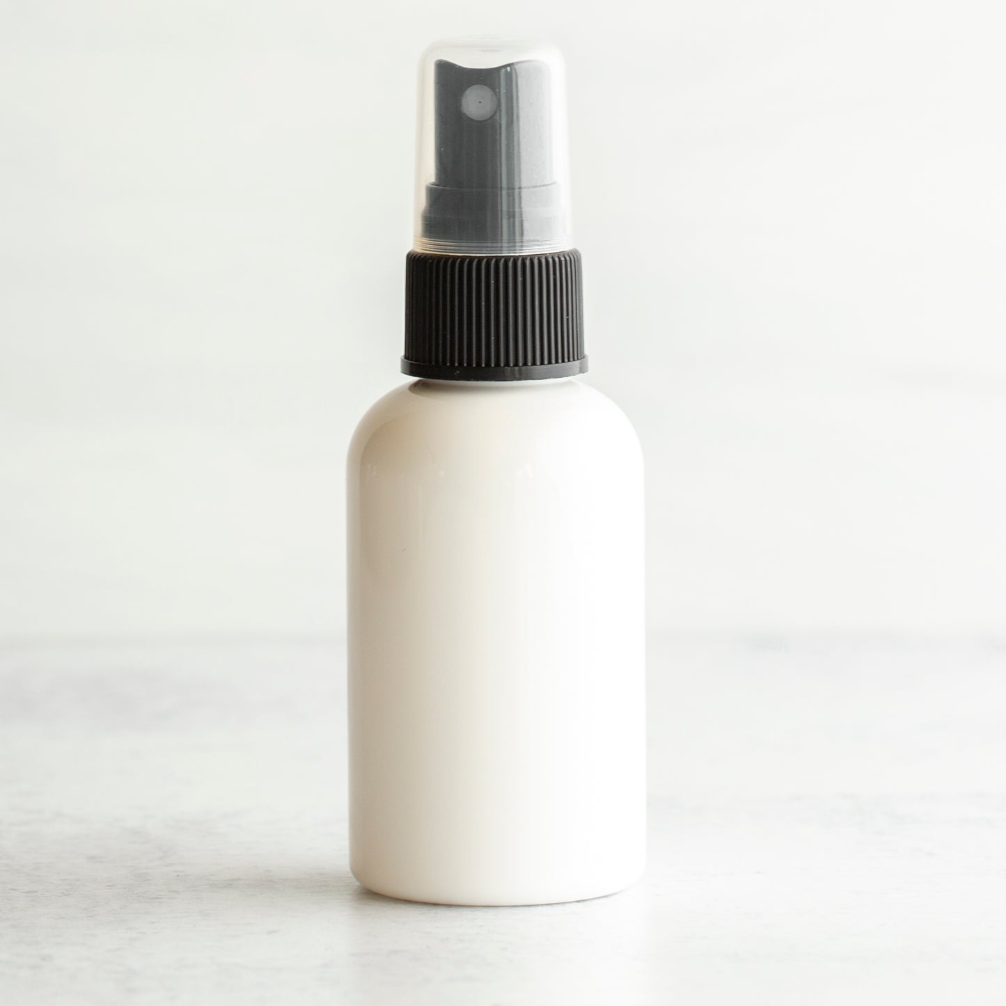 2 oz White PET Boston Round Bottle with 20-410 Black Fine Mist Sprayer