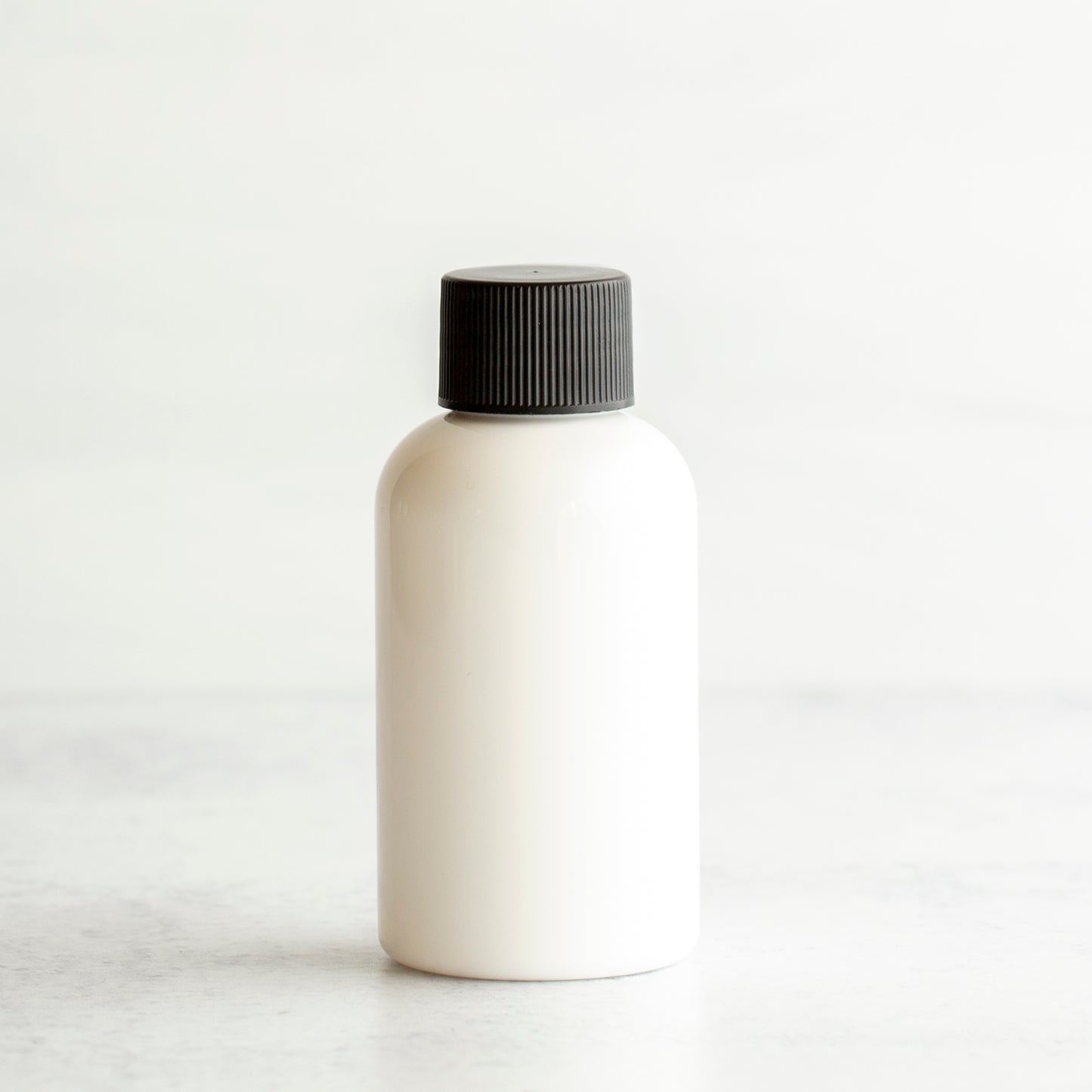 2 oz White PET Boston Round Bottle with 20-410 Black Ribbed Cap