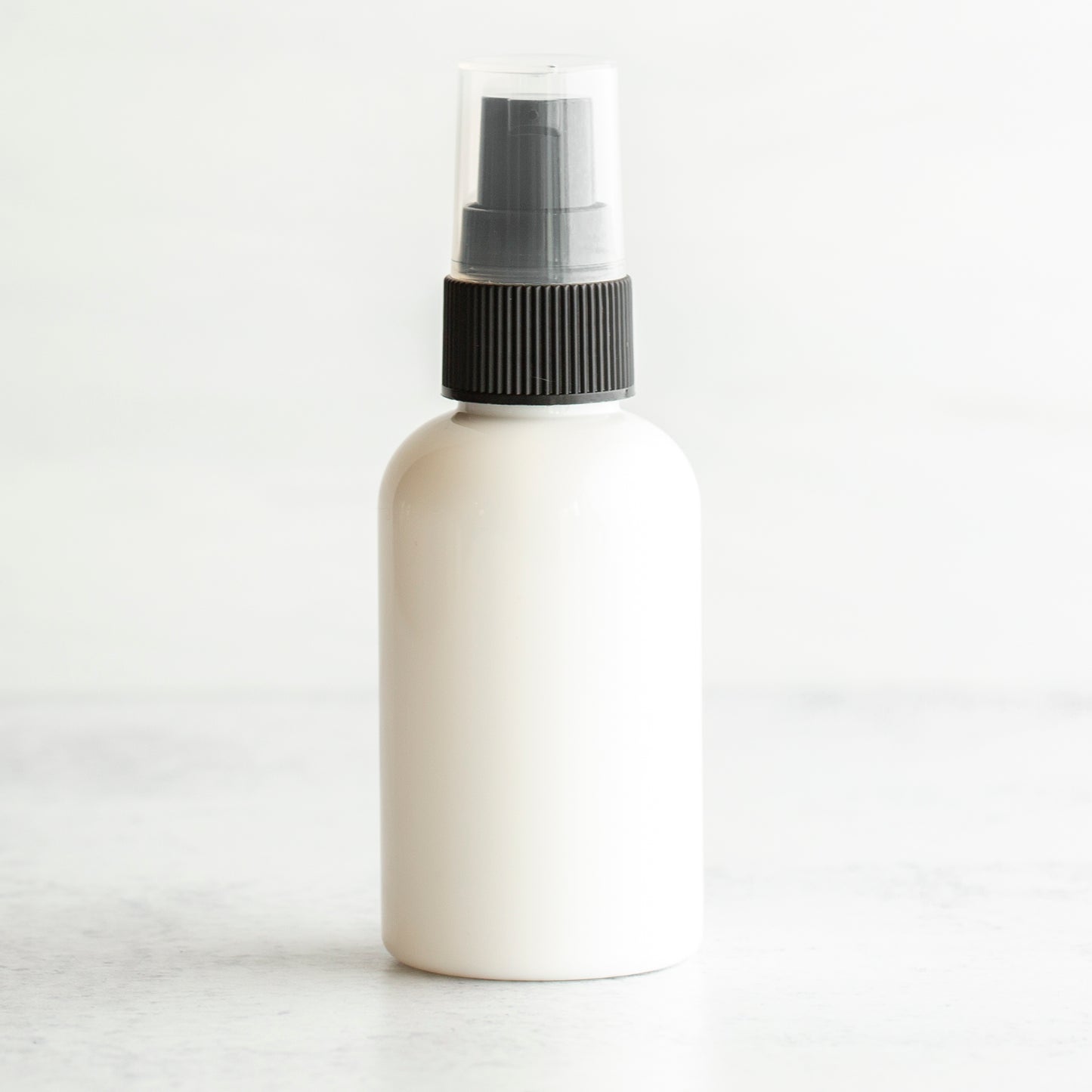 2 oz White PET Boston Round Bottle with 20-410 Black Treatment Pump