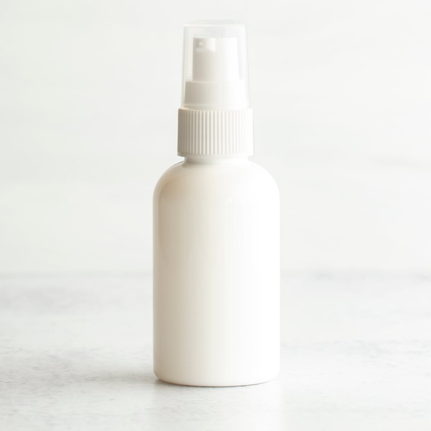 2 oz White PET Boston Round Bottle with 20-410 White Treatment Pump