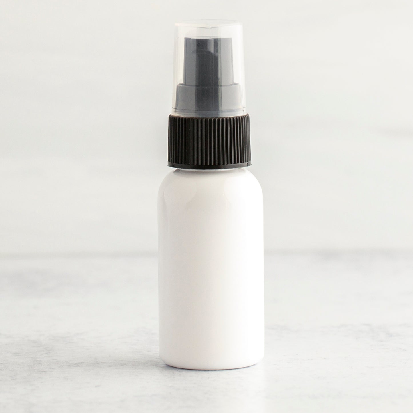 1 oz White PET Boston Round Bottle with 20-410 Black Treatment Pump